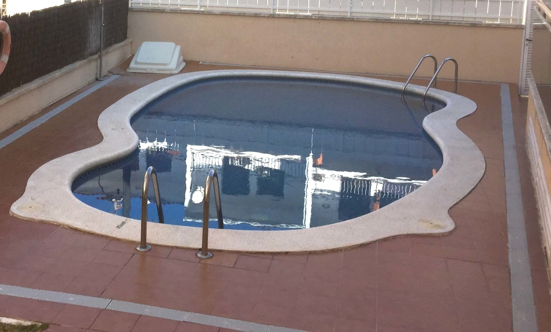 Piscina comunitaria del edificio con solárium y pocos vecinos